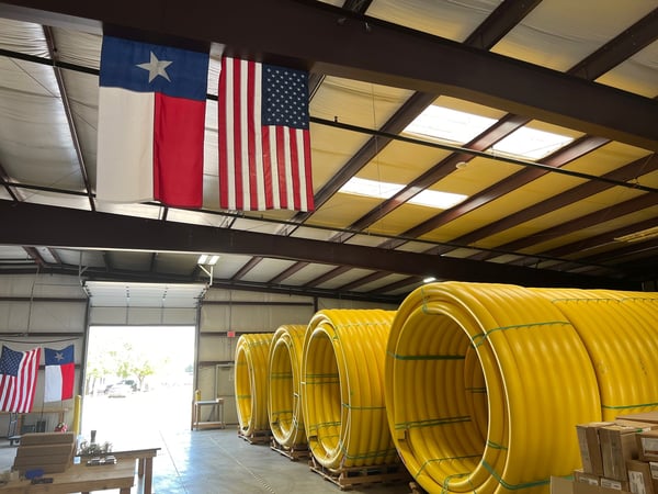 Yellow pipe coils inside warehouse, with American and Texas flag hanging from the ceiling